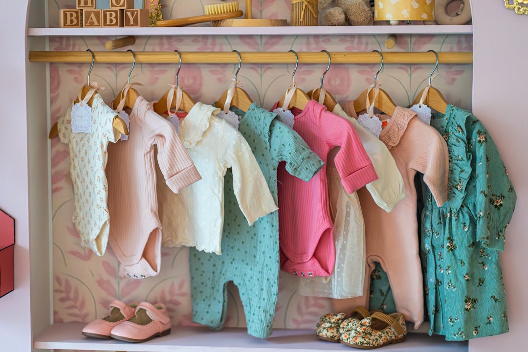 Baby clothes hanging on a rack with shoes below shoes